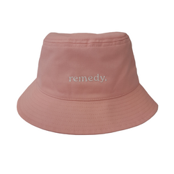 A front view of pink bucket hat with white embroidery branded 'remedy' on the front.