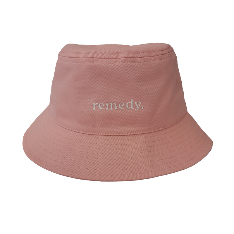A front view of pink bucket hat with white embroidery branded 'remedy' on the front.