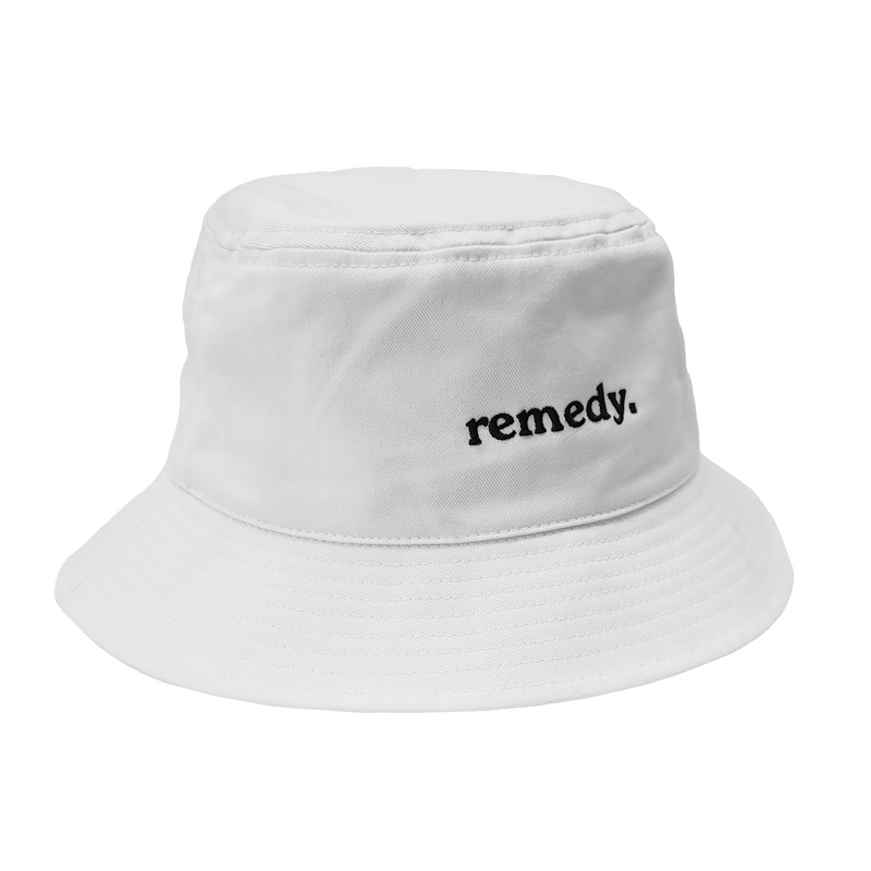 A side view of white bucket hat with black embroidery branded 'remedy' on the front.