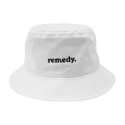 A front view of white bucket hat with black embroidery branded 'remedy' on the front.